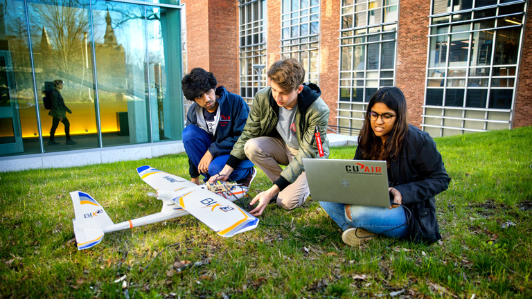 Three students working on a remote-controlled airplane