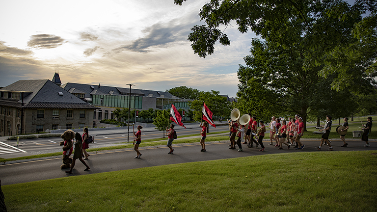The Big Red Bear leads members of the Cornell Marching Band past Klarman and Goldwin Smith halls during Reunion.